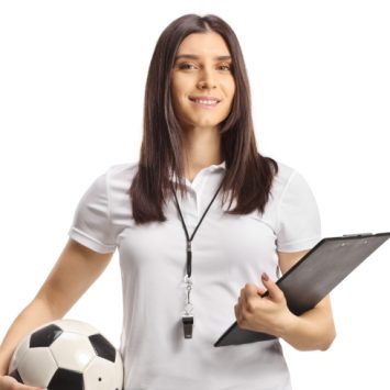 photo of woman in sportswear holding a football in one hand and a clipboard in the other