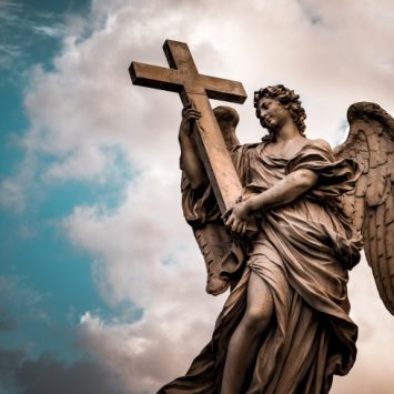 Photo of an angel statue against a dark, cloudy sky