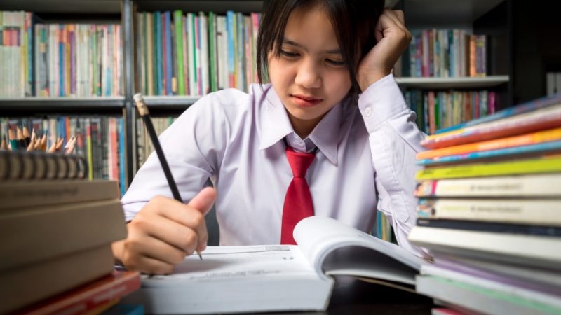 Close-up photo of teenage school student sat at desk, concentrating hard on reading a book