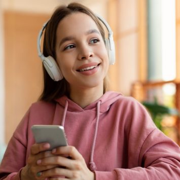 Photo of teenage girl using smartphone while wearing headphones