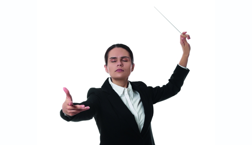 photo of an orchestra conductor with eyes closed and baton raised