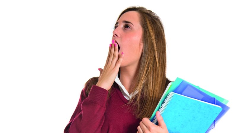 photo of teenage student holding folders and yawning