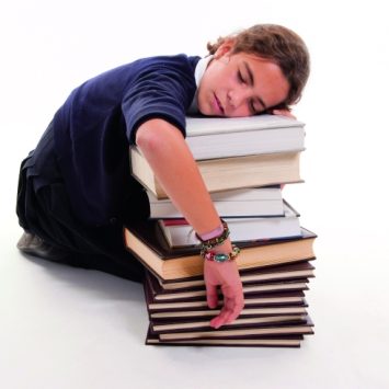 Photo of a student asleep against a stack of books