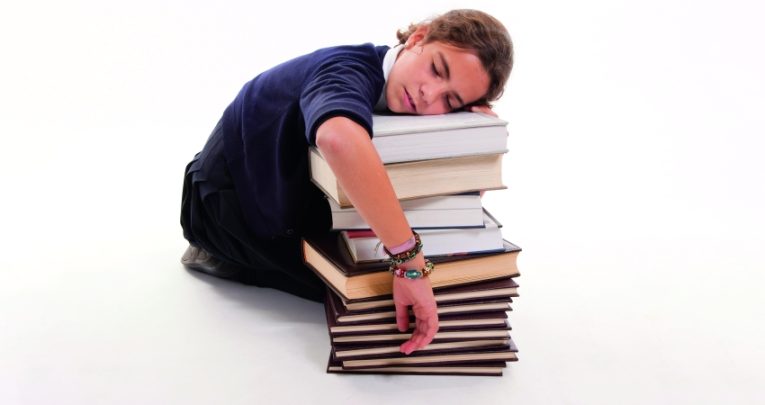 Photo of a student asleep against a stack of books