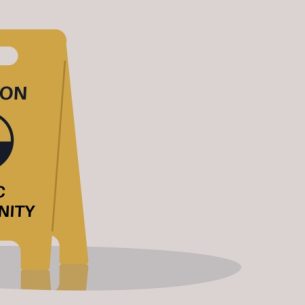 Mock-up illustration of a yellow wet floor warning sign that reads 'caution - toxic masculinity', representing misogyny in schools