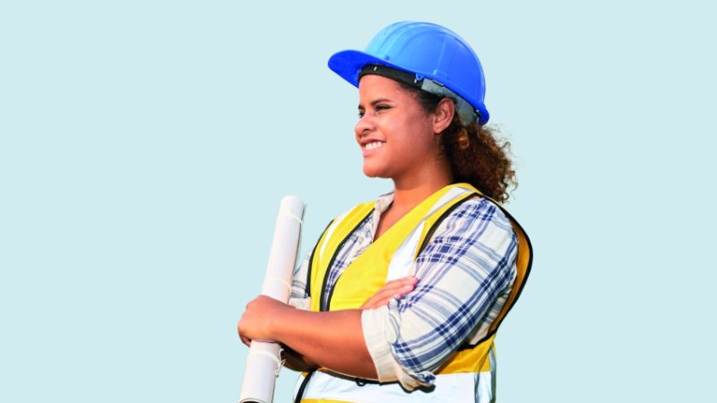 photo of a teenage girl wearing a high-vis vest and hard hat while holding a set of blueprints, representing women in STEM