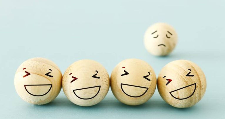 Photo of five wooden balls with faces. One is being left out, to represent friendship activities
