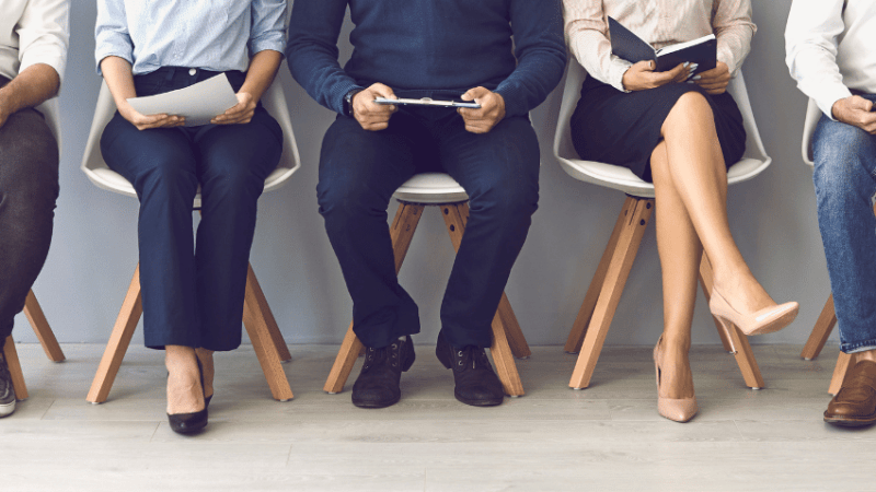 Body and legs of people waiting for interview, representing teacher interview questions