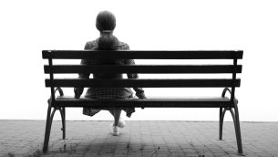 Photo of lonely figure sat on park bench, representing school absence