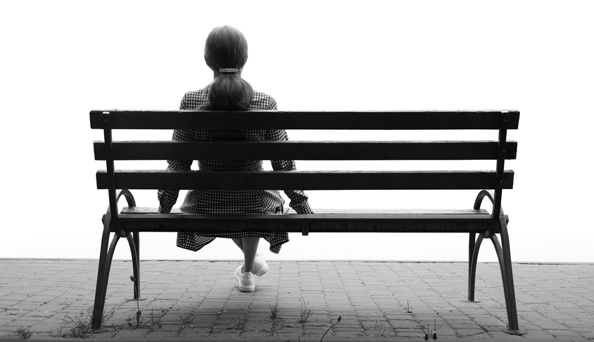 Photo of lonely figure sat on park bench, representing school absence