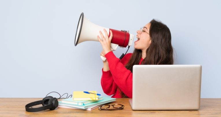 Photo of girl sat at desk talking into loudhailer