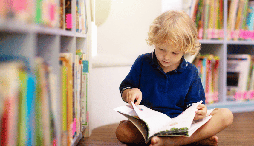 Boy reading book in library, representing KS1 reading comprehension