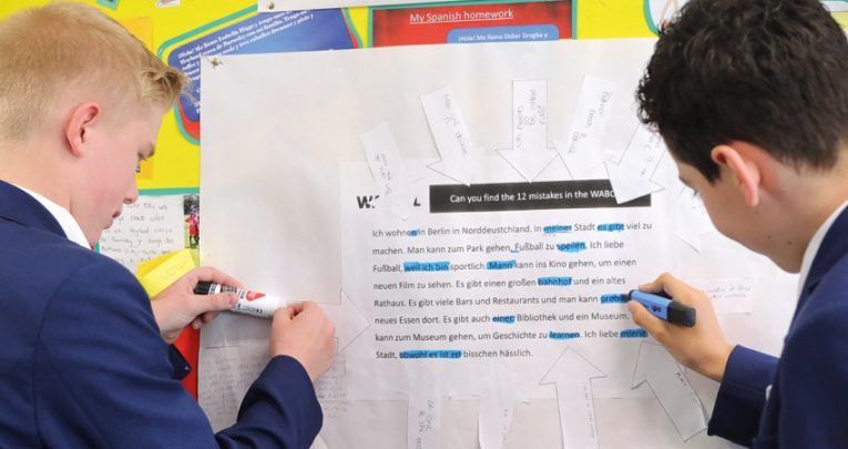 Photo of two teenage students completing a practical activity using a resource contained within a classroom display