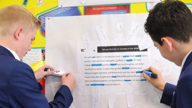 Photo of two teenage students completing a practical activity using a resource contained within a classroom display