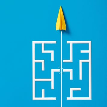 Abstract illustration of a paper aeroplane breaking through a simple wooden labyrinth, representing lesson difficulty