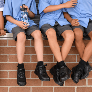 Children in school uniform sitting on wall, representing pupil premium