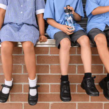 Children in school uniform sitting on wall, representing pupil premium