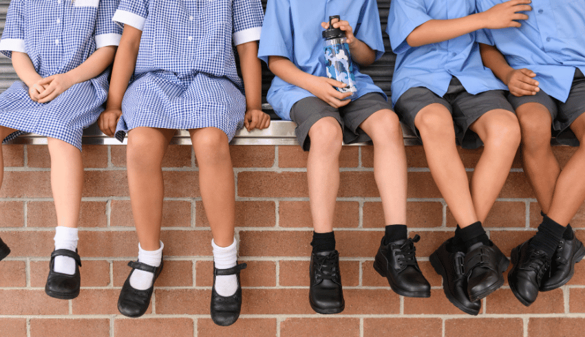 Children in school uniform sitting on wall, representing pupil premium