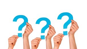 Three pairs of hands holding up cardboard question marks, representing questioning