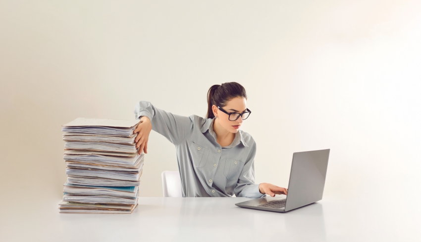 Woman shown sat in front of laptop going through a pile of written work, representing EHCP