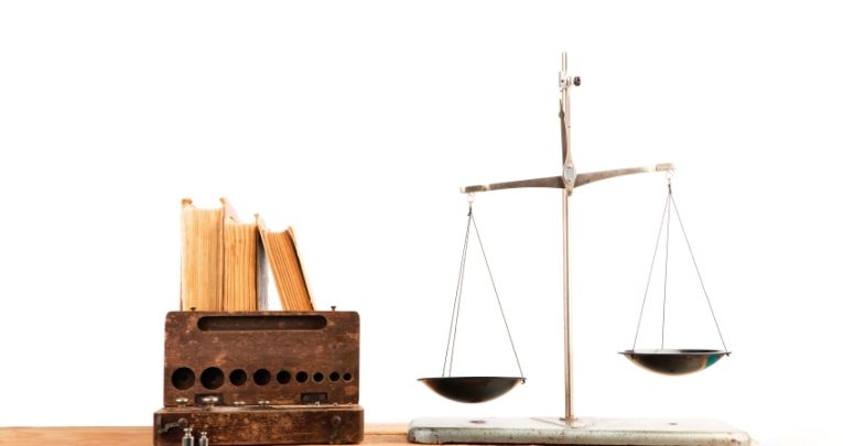 Photo of weighing scales beside a set of books to convey notion of justice