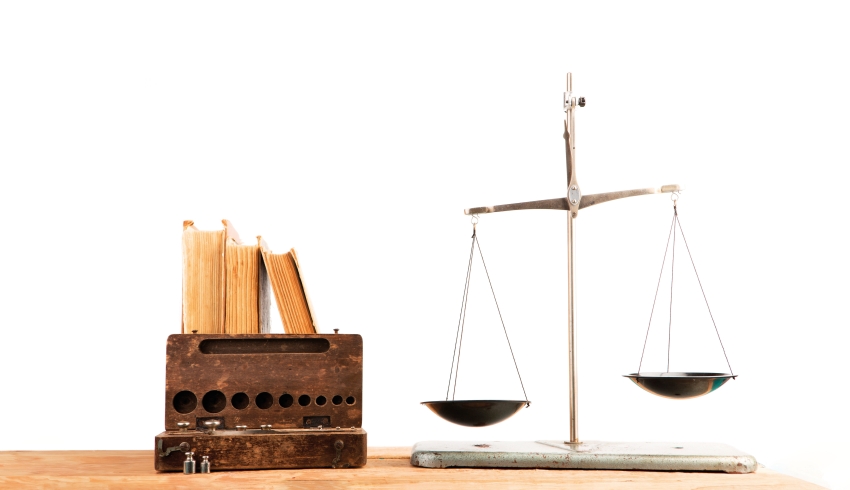 Photo of weighing scales beside a set of books to convey notion of justice