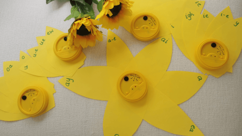 ideas for a creative writing task 'Flower' for teaching phonics. Yellow paper petals with letters written on the tips; talking tins make the center of the 'flowers'