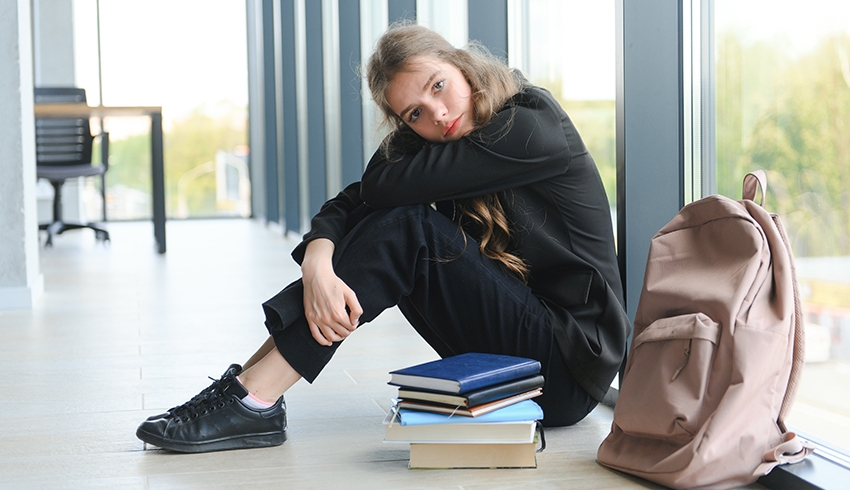 Photo of a teenage girl at school sat down and looking withdrawn, representing Autism Acceptance Week