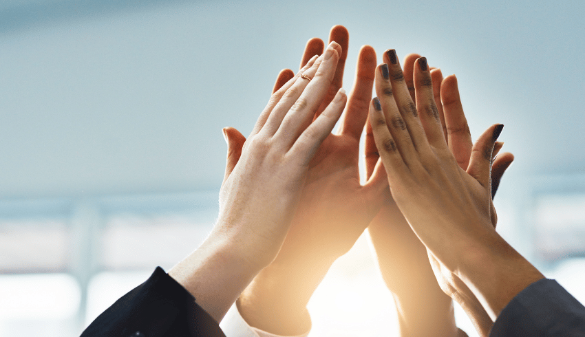 Multiple hands high-fiving, representing behaviour management in Early Years