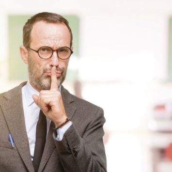 Photo of teacher with finger raised to his lips to illustrate notion of classroom silence