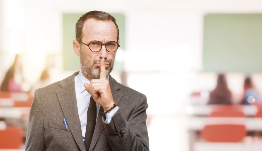 Photo of teacher with finger raised to his lips to illustrate notion of classroom silence