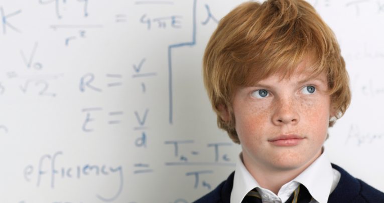 Student standing in front of maths problem on board, representing maths problem solving