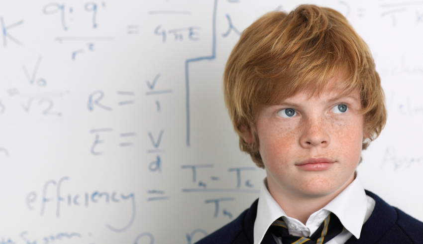 Student standing in front of maths problem on board, representing maths problem solving