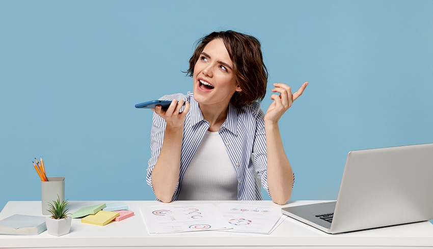 Photo of woman sat at desk recording verbal feedback into a smartphone