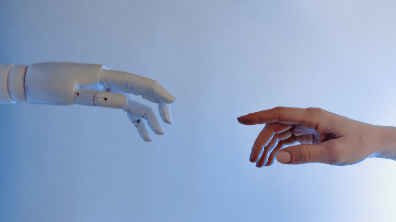 Human hand and robot hand reaching out to each other, representing AI in education