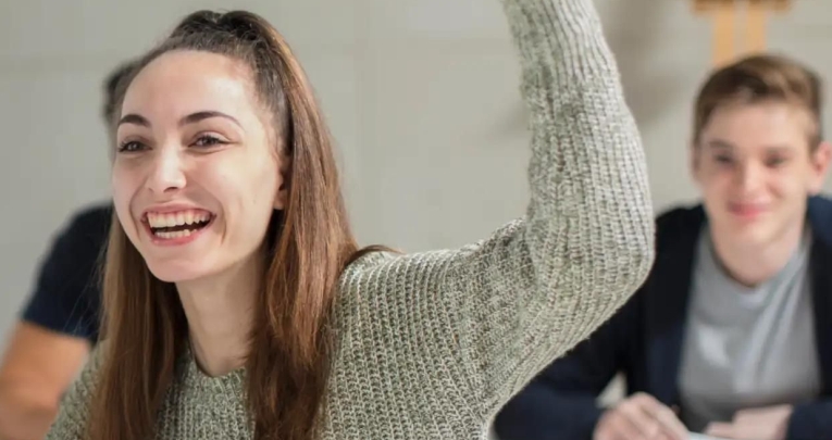 A female student putting her hand up in class