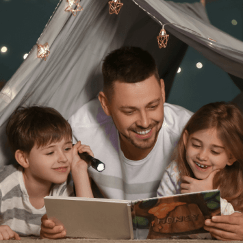 Boy, man and girl reading a book together, representing closing the reading gap
