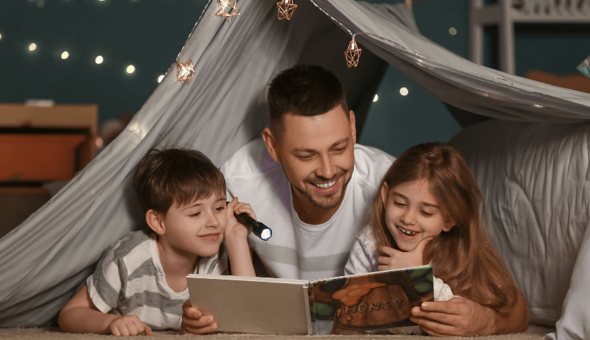 Boy, man and girl reading a book together, representing closing the reading gap