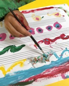 A child painting on music manuscript paper