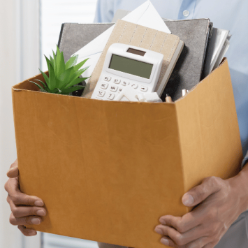 Man holding box of objects from desk, representing jobs for ex teachers