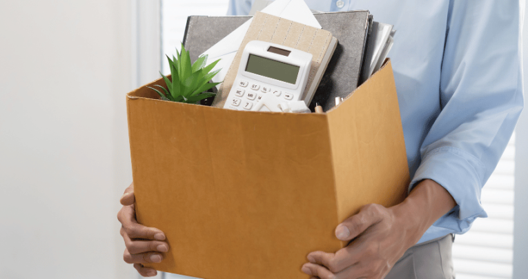 Man holding box of objects from desk, representing jobs for ex teachers