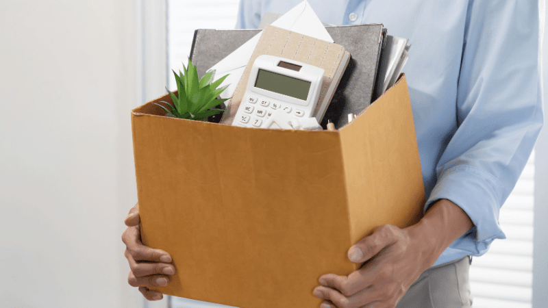 Man holding box of objects from desk, representing jobs for ex teachers