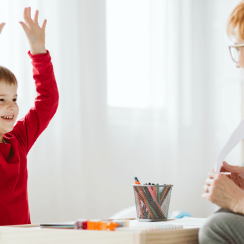 Happy boy sitting with teacher, representing ADHD Awareness Month