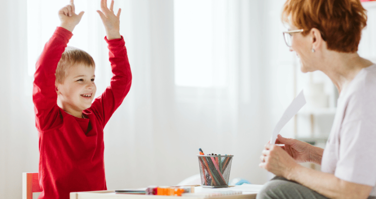 Happy boy sitting with teacher, representing ADHD Awareness Month