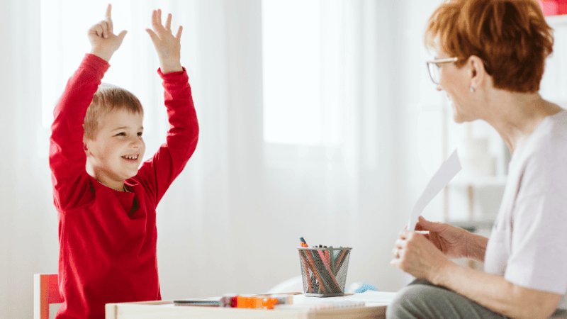 Happy boy sitting with teacher, representing ADHD Awareness Month