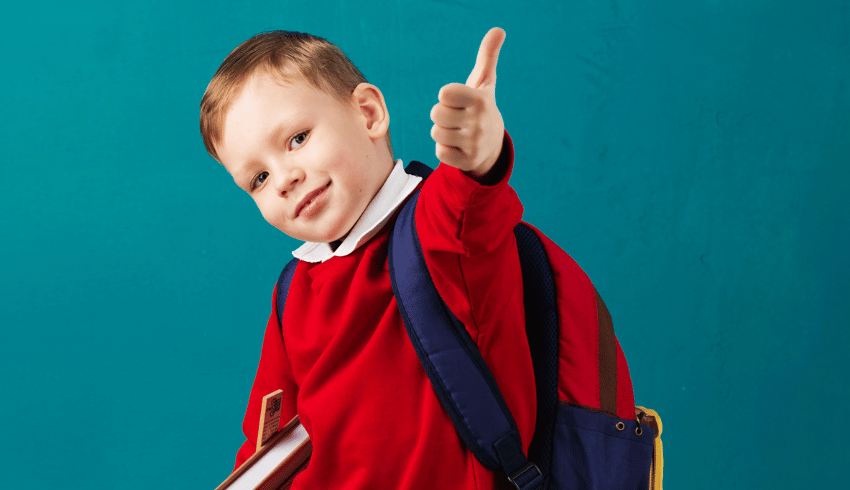 Boy with ADHD wearing school uniform and doing a thumbs up gesture