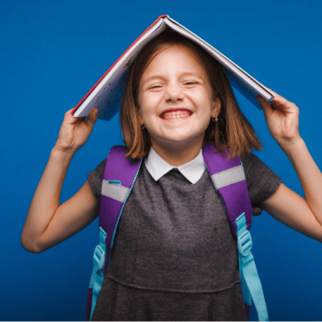 Smiling girl with non-fiction book on her head