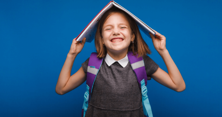 Smiling girl with non-fiction book on her head