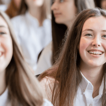 Two girls smiling in school assembly