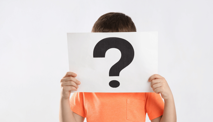 Child holding question mark in front of face